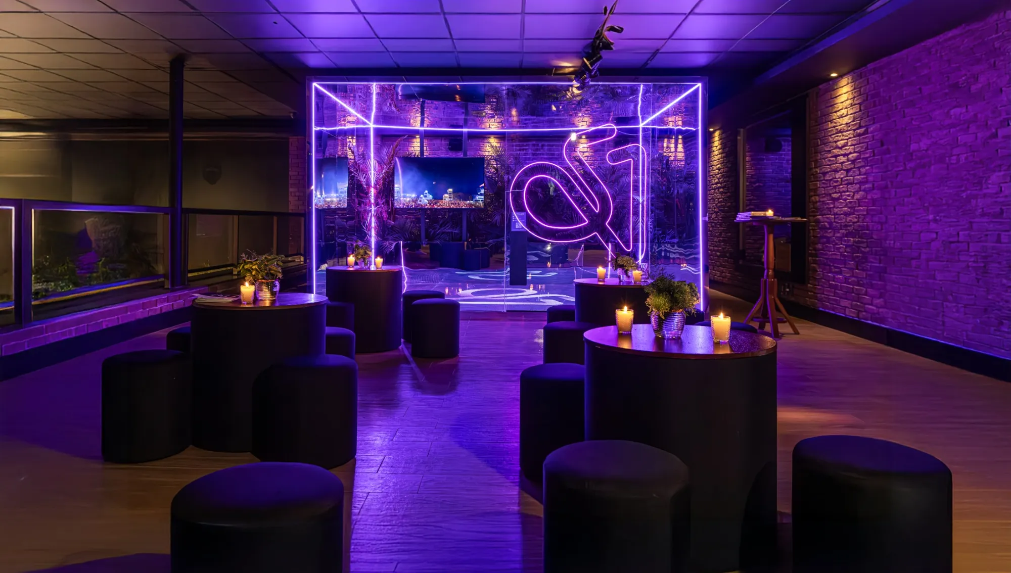 Lounge corporativo com bistrôs, puffs e iluminação roxa